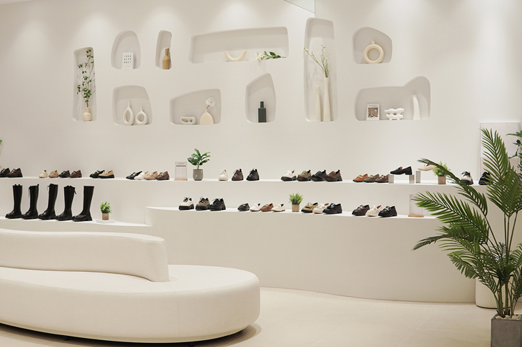 邵雨薇代言D+AF LALAPORT台中店 女鞋陳列 流行女鞋 純白色系空間形成的弧線流暢地至牆面，運用不規則線條的拱形洞穴形狀點綴牆面，使偌大的空間整體產生柔和及設計感氛圍！呈現細膩多變的視覺感，讓空間更加舒適溫和。