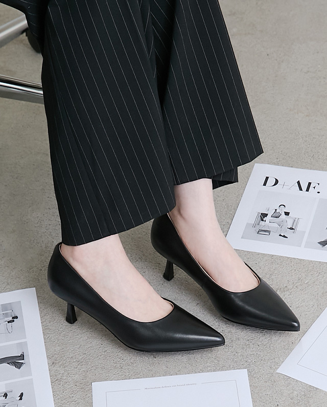 5CM真皮全能高跟鞋。特寫黑色尖頭真皮高跟鞋搭配條紋西裝褲，完美示範俐落職場穿搭。搭載雙重雲彈科技 五合一全能鞋墊，可以奔跑的高跟鞋，解決通勤腳痠痛點。懂你的腳，立即體驗 5 公分黃金高度的無痛腳感！